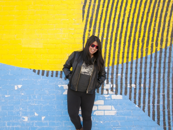A woman standing in front of a colorful mural