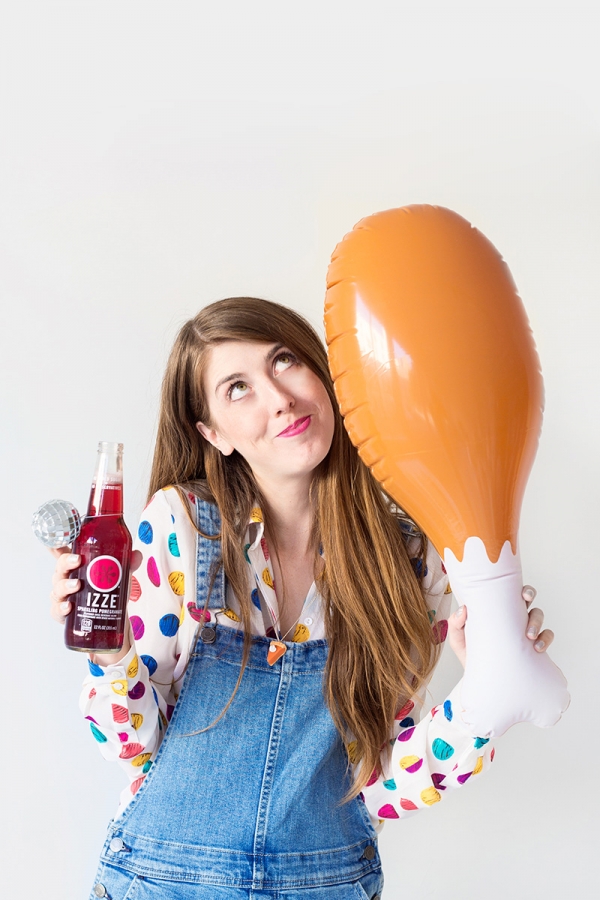 Someone holding an izze and a blow up chicken leg