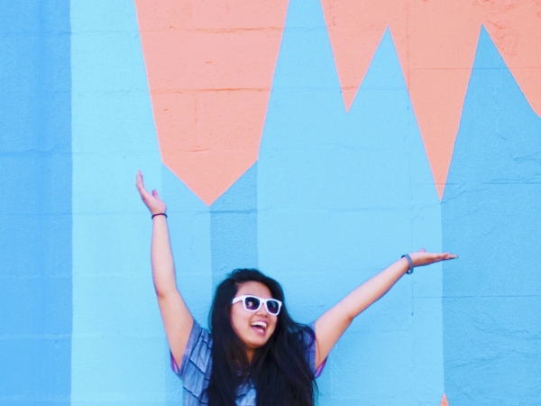 A woman standing in front of a colorful mural