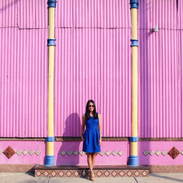 A woman standing in front of a pink wall