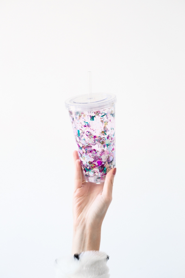 A woman holding a cup with sparkles