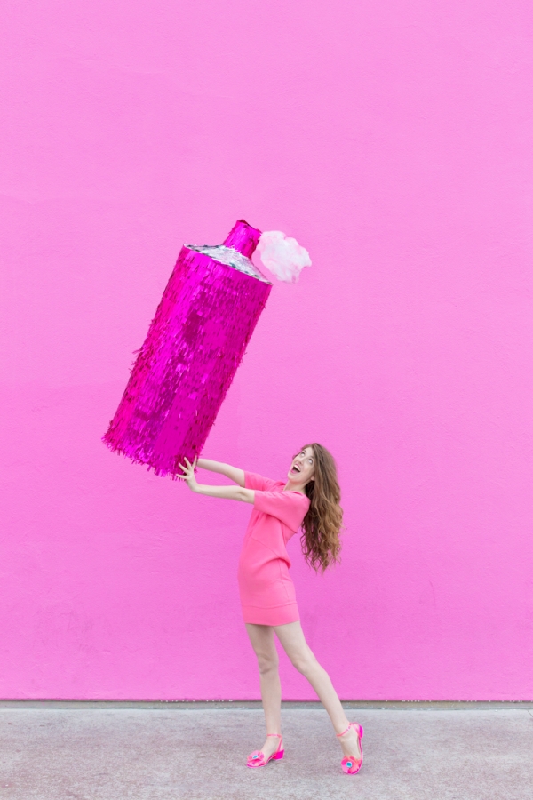 A woman holding a pink hairspray pinata