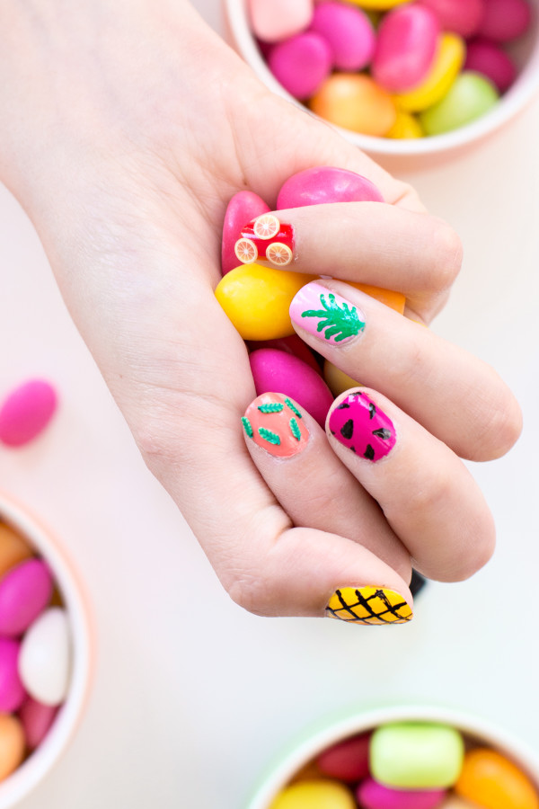Someone with colorful nail polish holding candy