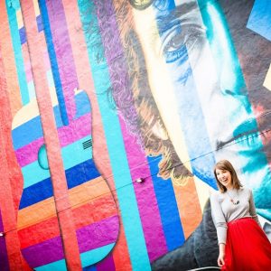 A woman standing in front of a colorful mural