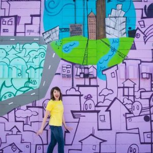 A woman standing in front of a mural