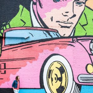 A woman standing in front of a colorful mural