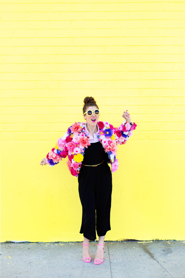 A woman standing in front of a yellow wall with a floral jacket