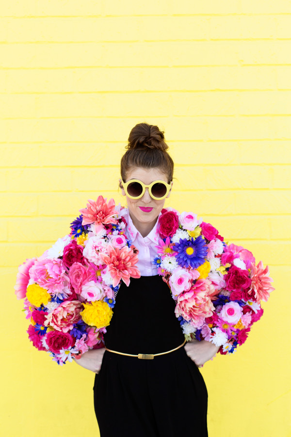 A woman wearing a floral jacket in front of a yellow wall