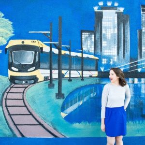 A woman standing in front of a blue mural