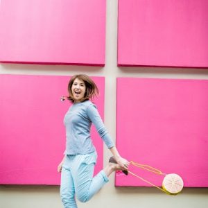 A woman standing in front of a pink wall