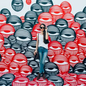 A woman standing in front of a eye-patterned wall