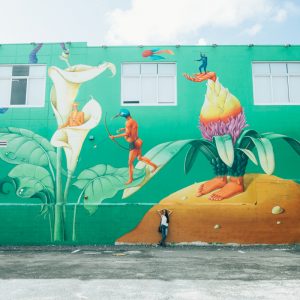 A woman standing in front of a colorful mural