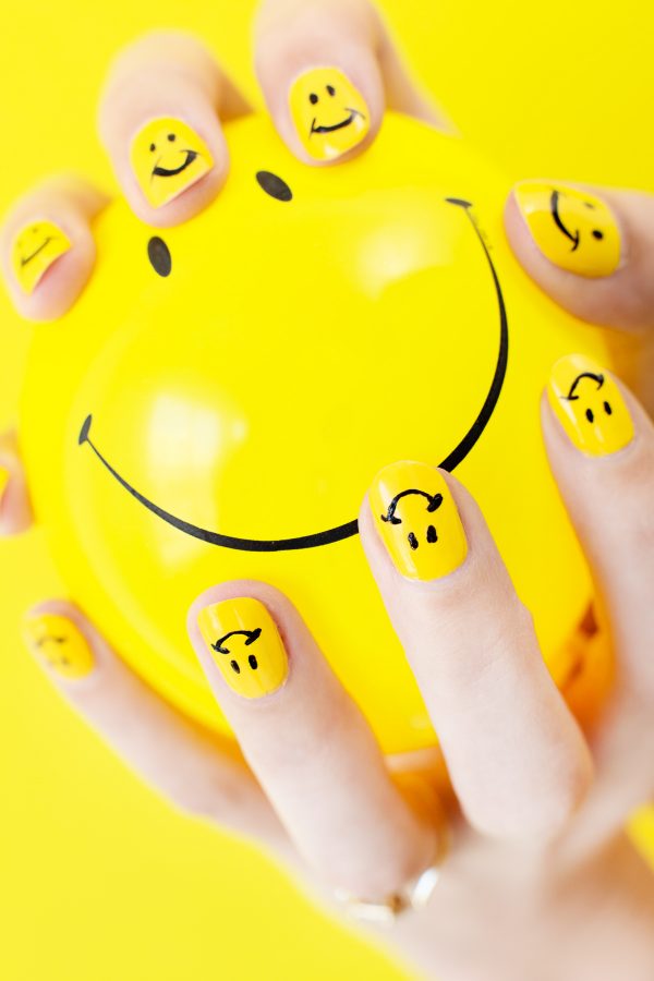 Someone with yellow nails holding a yellow balloon