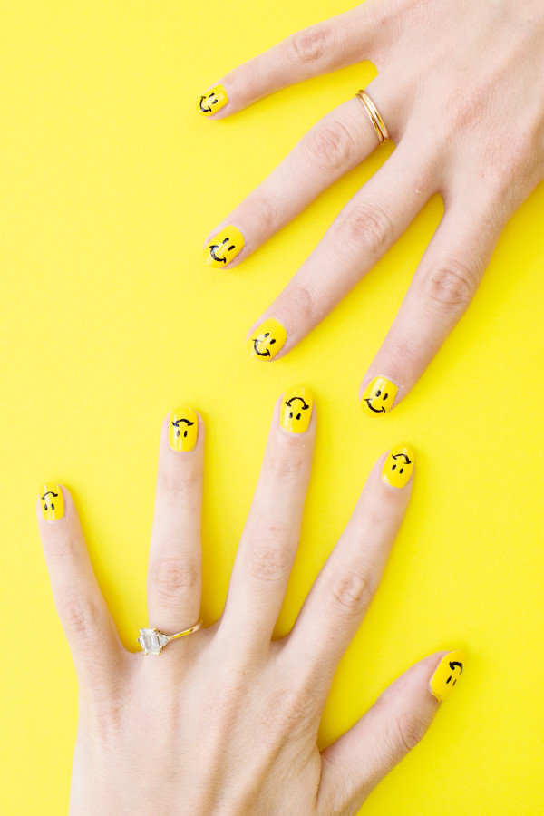 Someones hands with yellow nails on a yellow surface