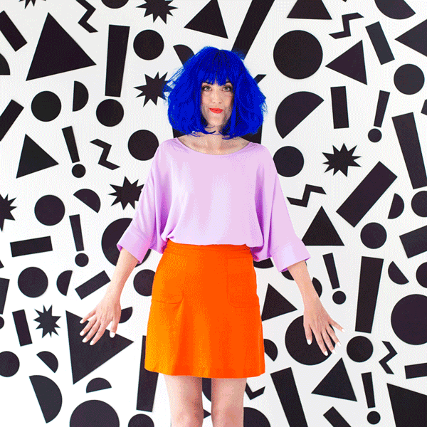 Someone posing in a costume in front of a patterned wall