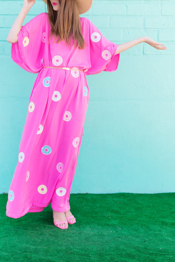A woman wearing a pink dress with donuts on it