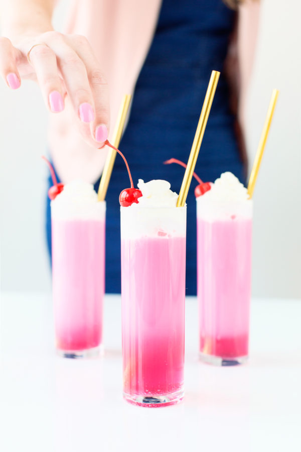 Three glasses with gold straws and pink liquid