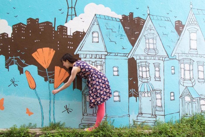 A woman standing in front of a colorful mural