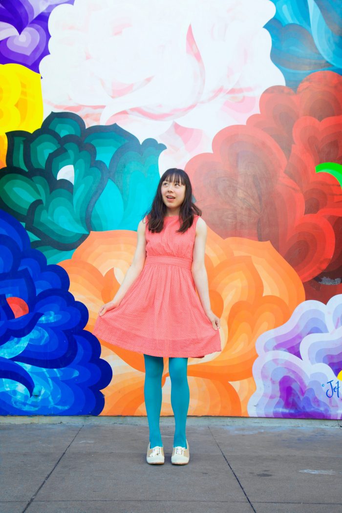 A woman standing in front of a colorful wall