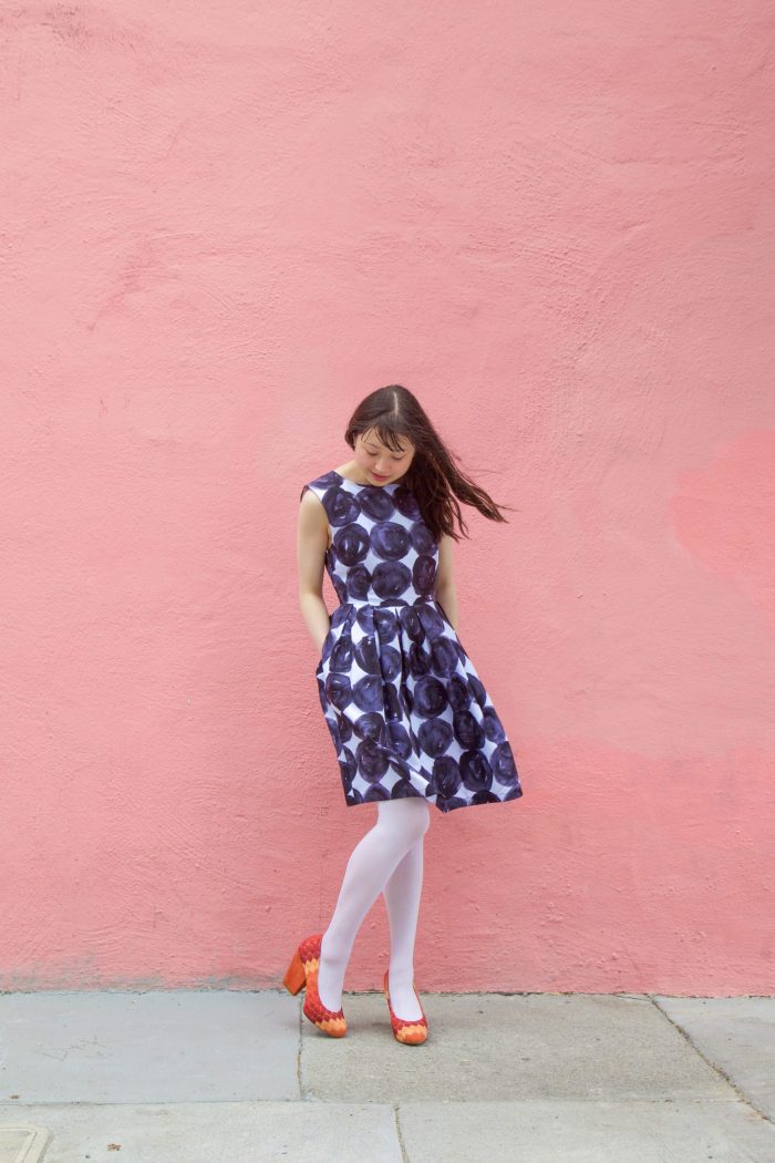 A woman standing in front of a pink wall