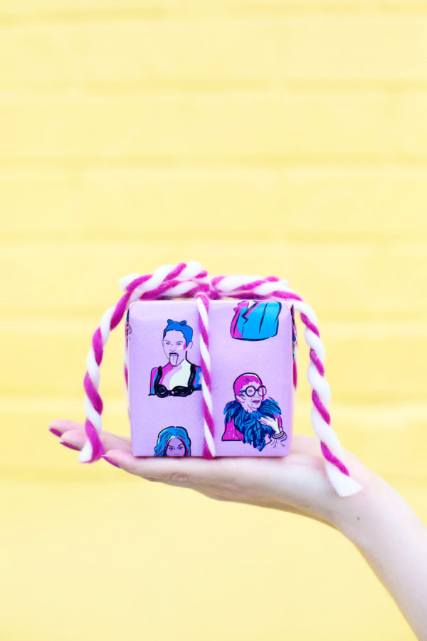 Someone holding a present in front of a yellow wall