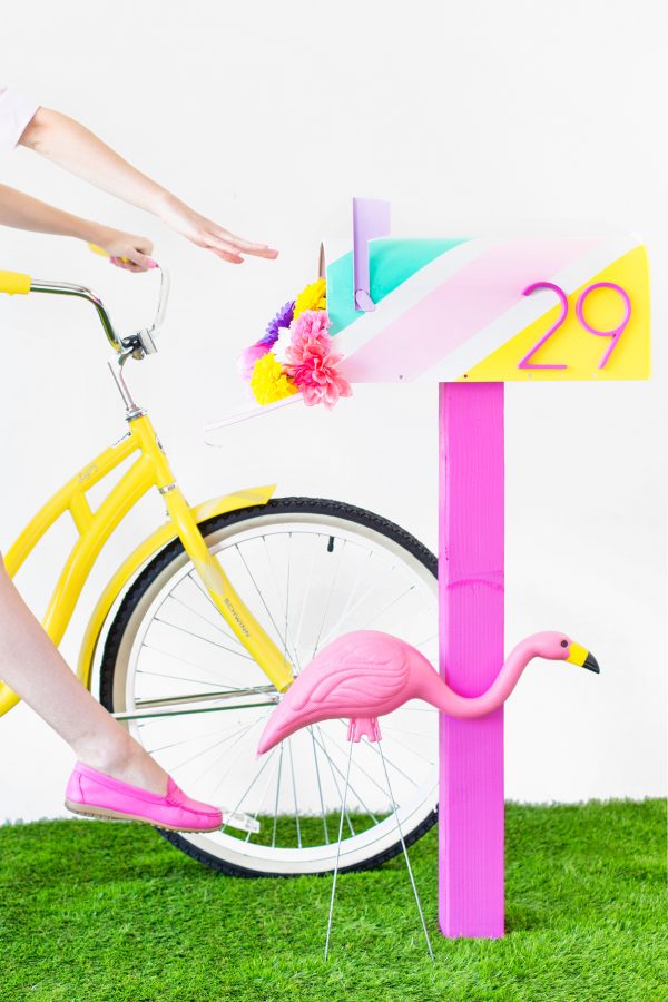 A mailbox with a flamingo and a bicycle