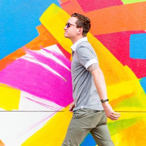 A man in front of a colorful mural