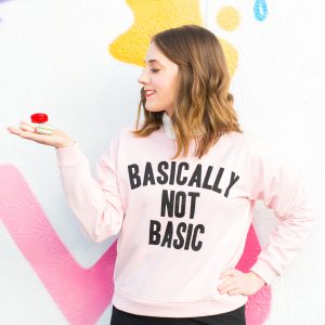A woman wearing a pink sweatshirt holding macaroons