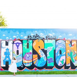 A woman in front of a colorful wall with "Houston" written on it