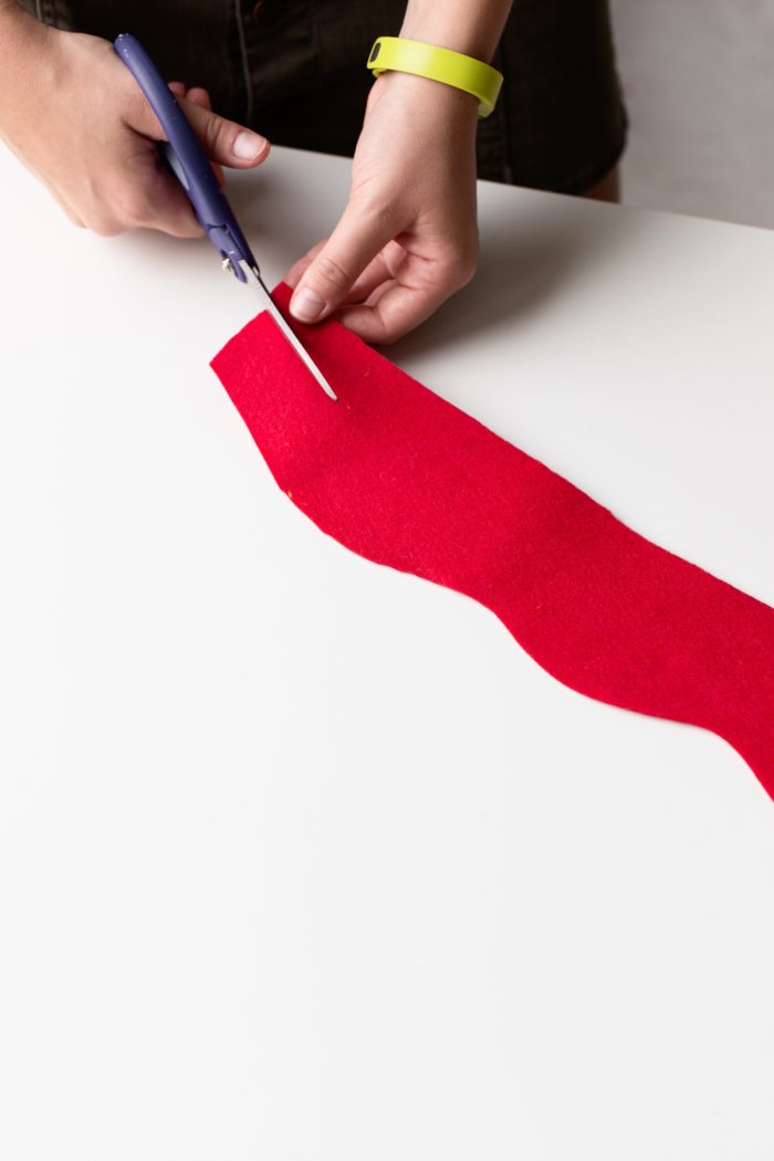 Hot Dog Outfit Hand cutting a piece of red felt.