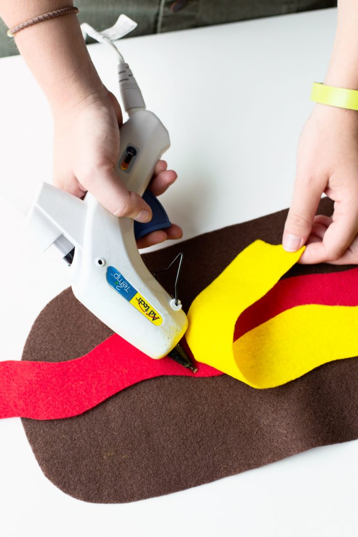 Easy Hot Dog Outfit Someone gluing yellow felt to brown and red felt.