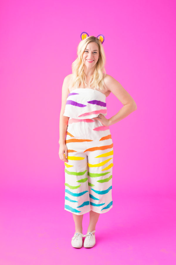 A girl wearing a white romper with rainbow stripes on it