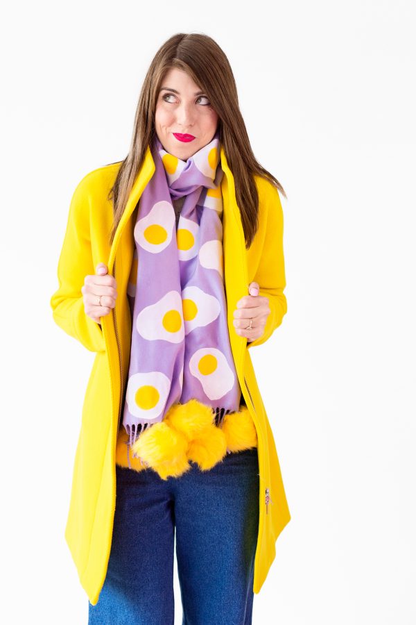 A woman wearing a purple egg scarf and yellow jacket