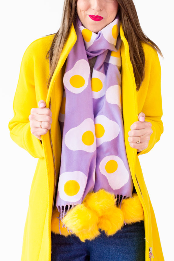 A person wearing a purple egg scarf and a yellow jacket