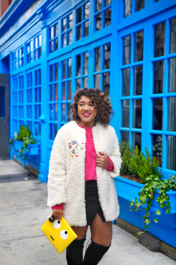 A woman wearing a pink shirt in front of a blue building