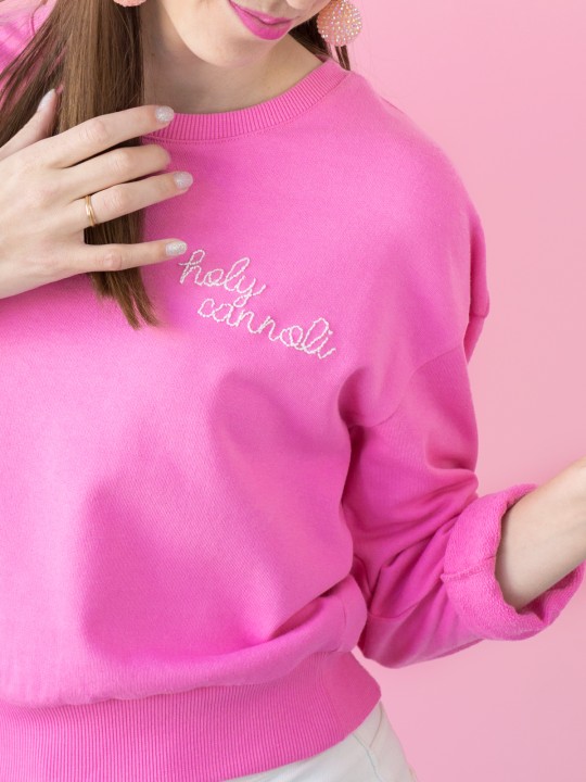 The corner of a pink crew neck with embroidered words on it