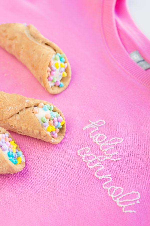 White embroidery on a pink crew neck and cannolis