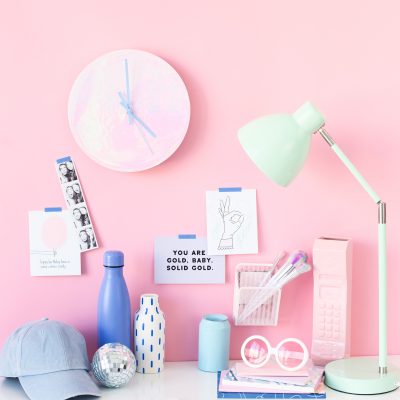 A bunch of items sitting on a desk in front of a pink wall