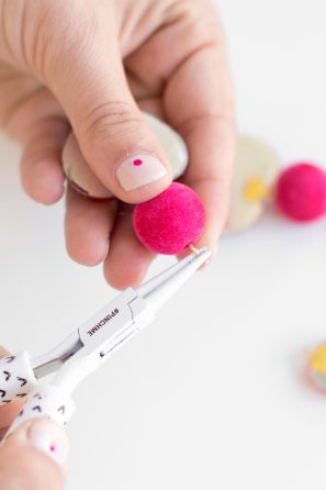 Someone holding a tool and a pink felt ball