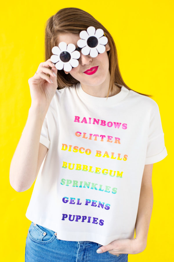 A woman wearing a white shirt with rainbow words