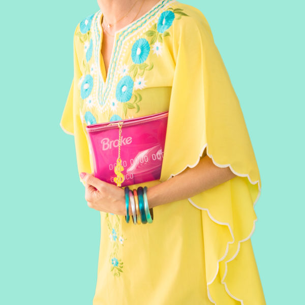 A girl in a yellow dress holding a pink bag