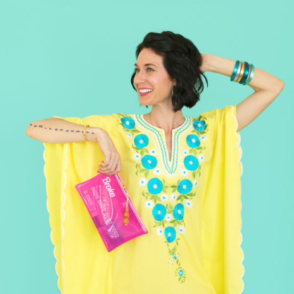 A person wearing a yellow dress and holding a pink bag