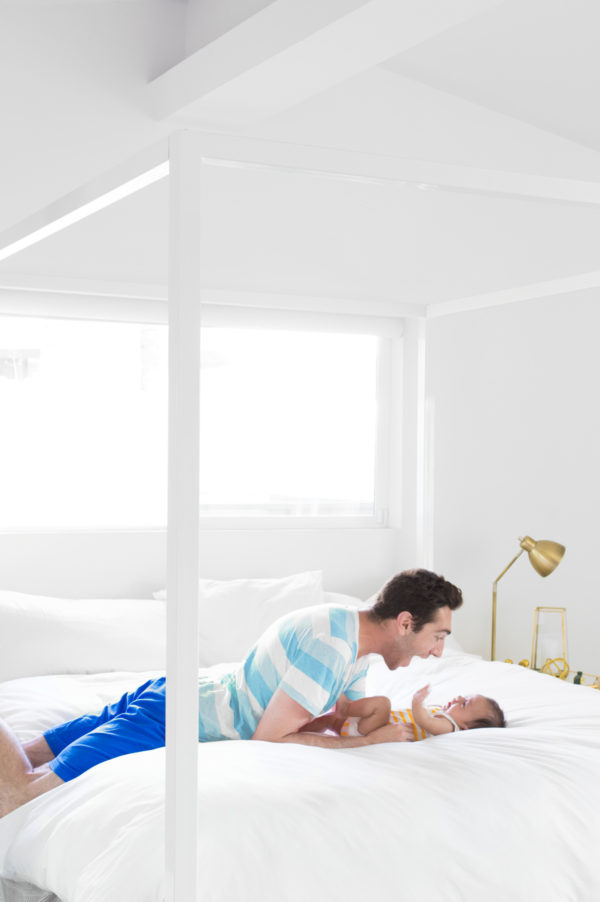 A man and a baby sitting on a bed