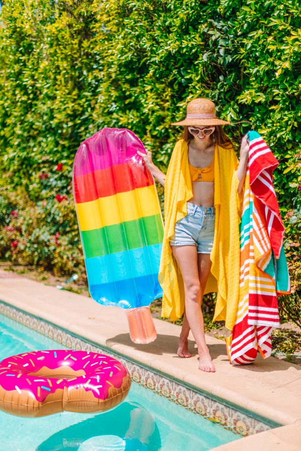 A person wearing a hat holding a rainbow floatie