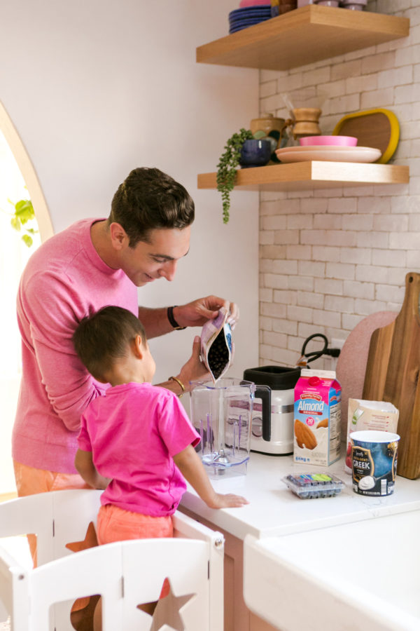 A person and a little boy that is standing in the kitchen