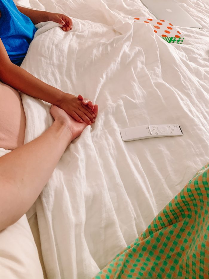 Two people holding hands on a bed
