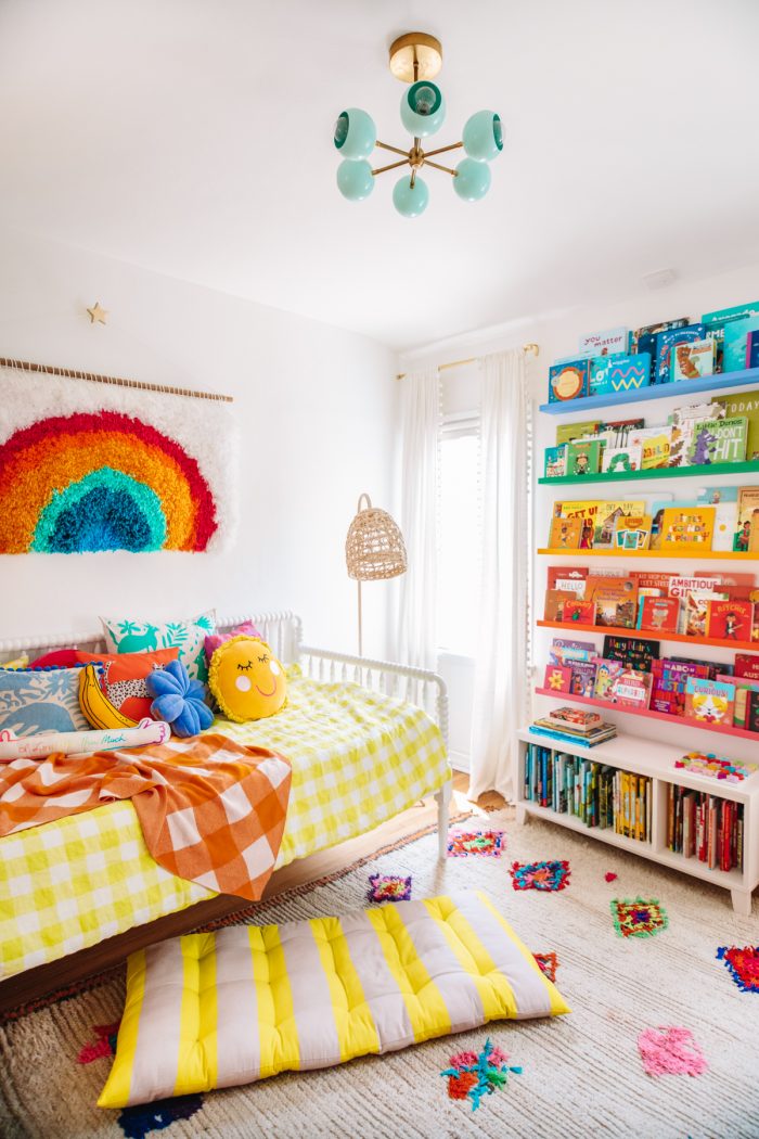 A colorful bedroom with a daybed and bookshelf