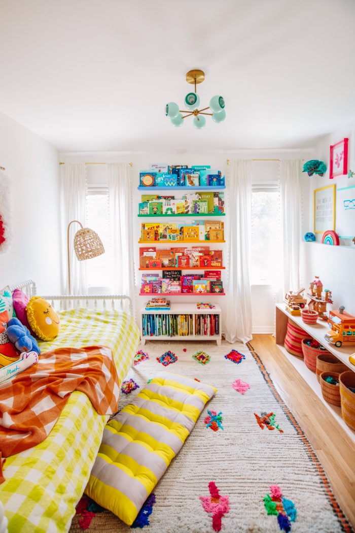 A bedroom with rainbow bookshelves