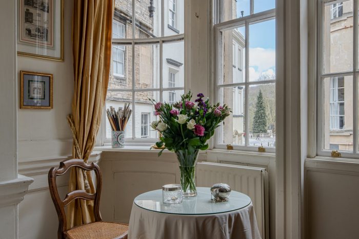A vase of flowers on a table next to a window