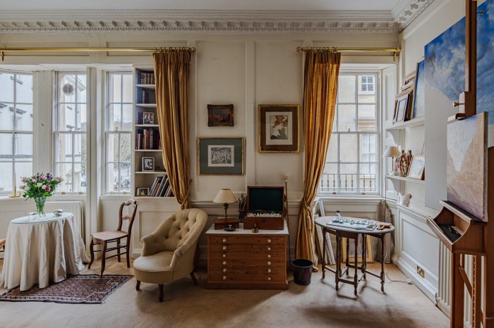A living room with furniture and two large windows